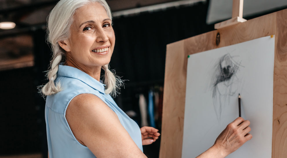 lifelong_learning_image A senior woman paints and smiles to one side.